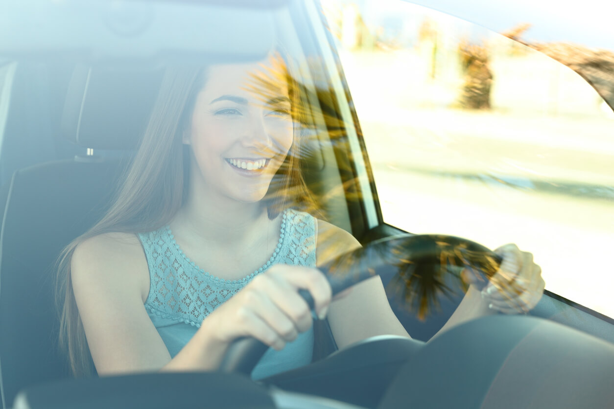 Portrait of a young happy attentive driver woman driving a car on the road
