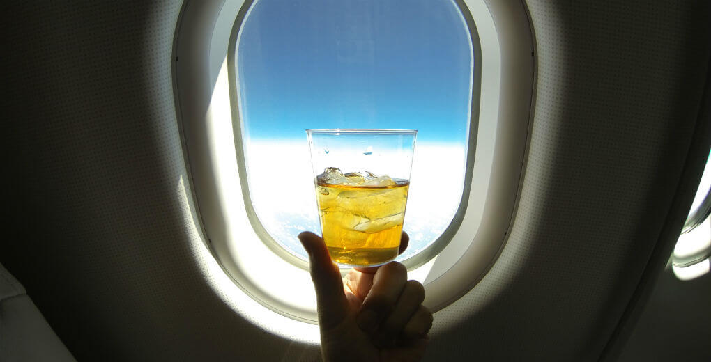 Person holding a drink on a plane