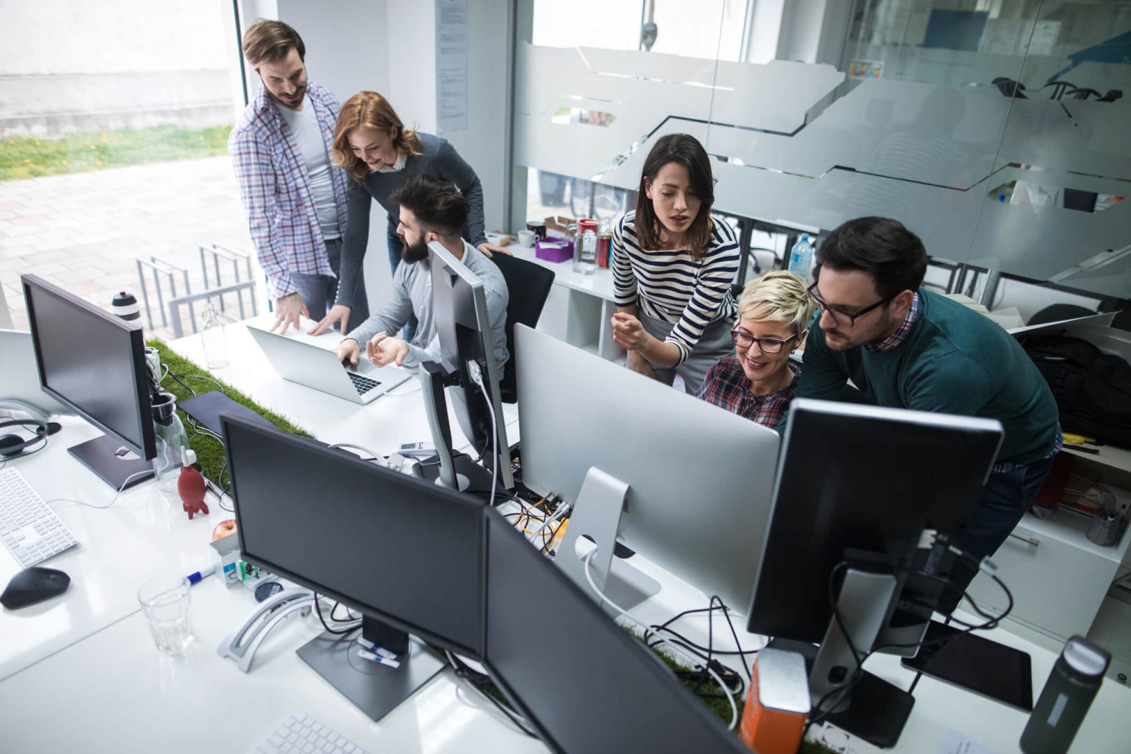  A group of coworkers brainstorm ideas in front of a computer in an office.