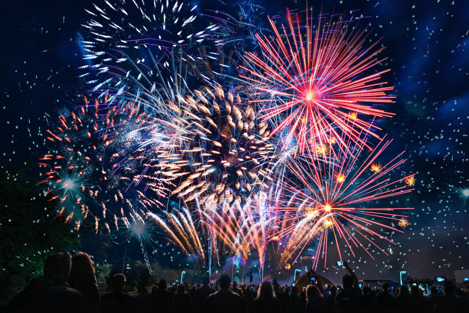 Silhouettes of a crowd cheering in front of fireworks