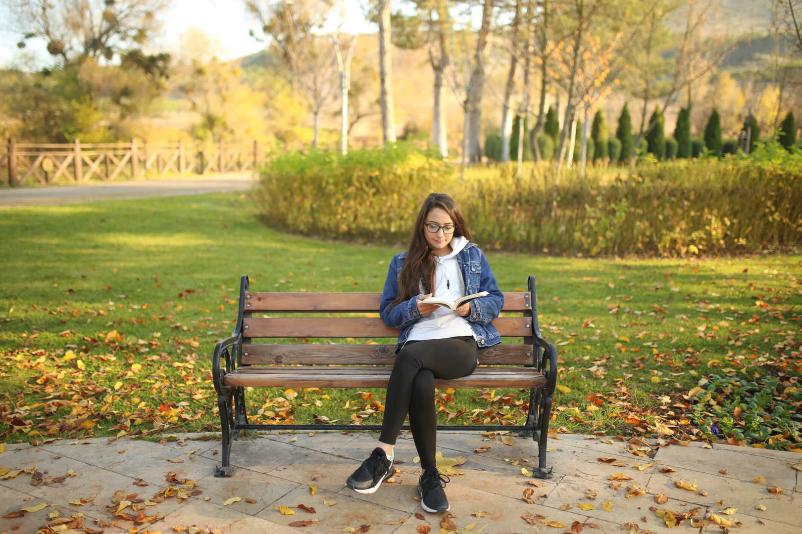 Woman sitting on the bench at the park and reading a book.