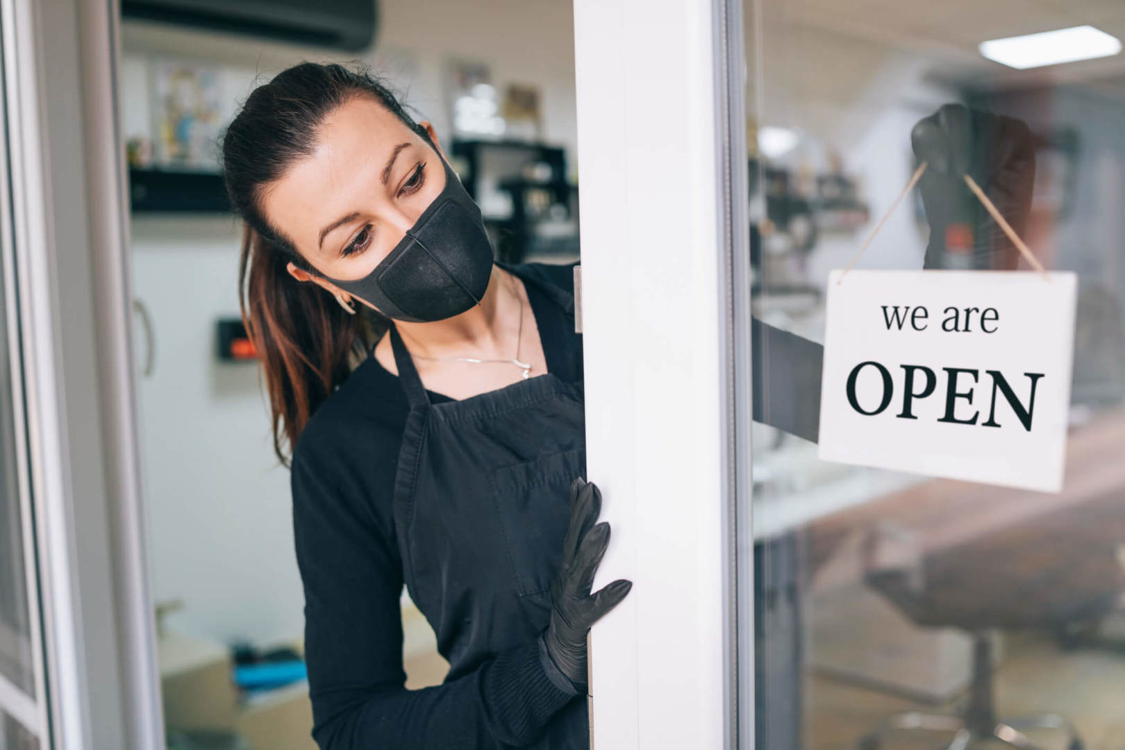 Happy business owner hanging an open sign during COVID-19